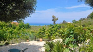 A patio with stone flooring and two green lounge chairs. - Holiday House Angelos A on Agios Gordios Beach (Corfu)