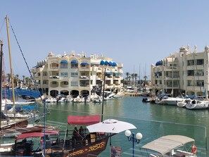Boats docked at the marina, surrounded by buildings with balconies and arches.