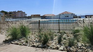 Un barrio residencial con piscina, valla de madera y casas al fondo.