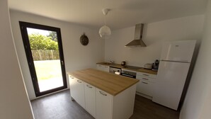 Een kleine keuken met witte kasten, een houten aanrechtblad en een ingebouwde oven.