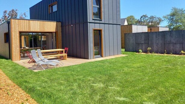 Ein modernes, zweistöckiges Haus mit einer Holzterrasse und einer Patio.