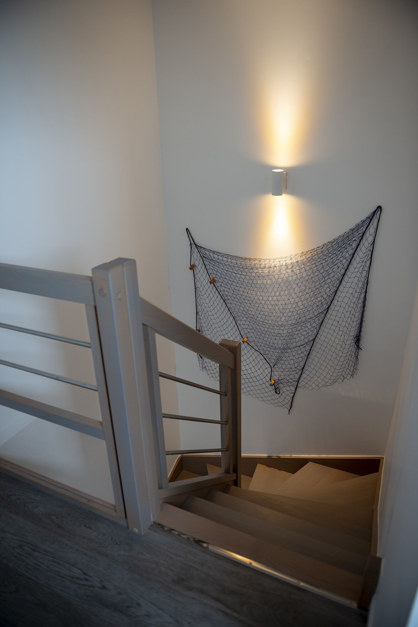 A staircase with a wooden handrail and a wall-mounted light fixture.