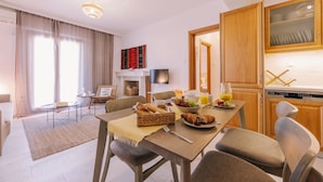 Ein modernes Wohnzimmer mit einer Couch, einem Couchtisch und einem Essbereich, gedeckt für ein Frühstück.