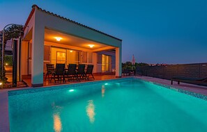 Une maison moderne dotée d’une piscine, d’un espace salon extérieur et d’un patio.