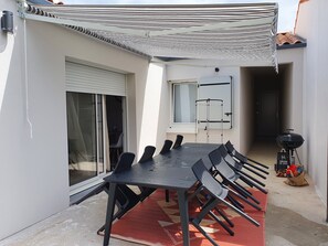 Eine Terrasse mit Tisch, Stühlen, Grill und einer Ablage.