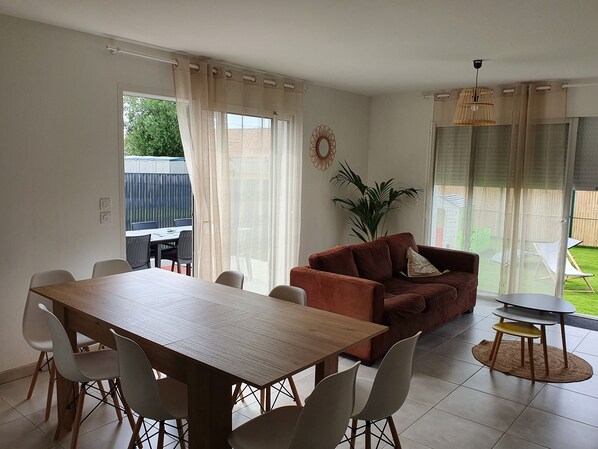A dining area with a wooden table and chairs, a brown sofa, and a small round table with a chair.