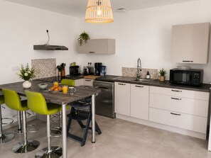 Une cuisine moderne avec un coin repas, comprenant une table avec des chaises, un four à micro-ondes, un évier et un lave-vaisselle.