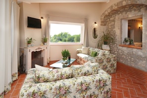 A living room with a fireplace, floral sofa, and a stone wall.