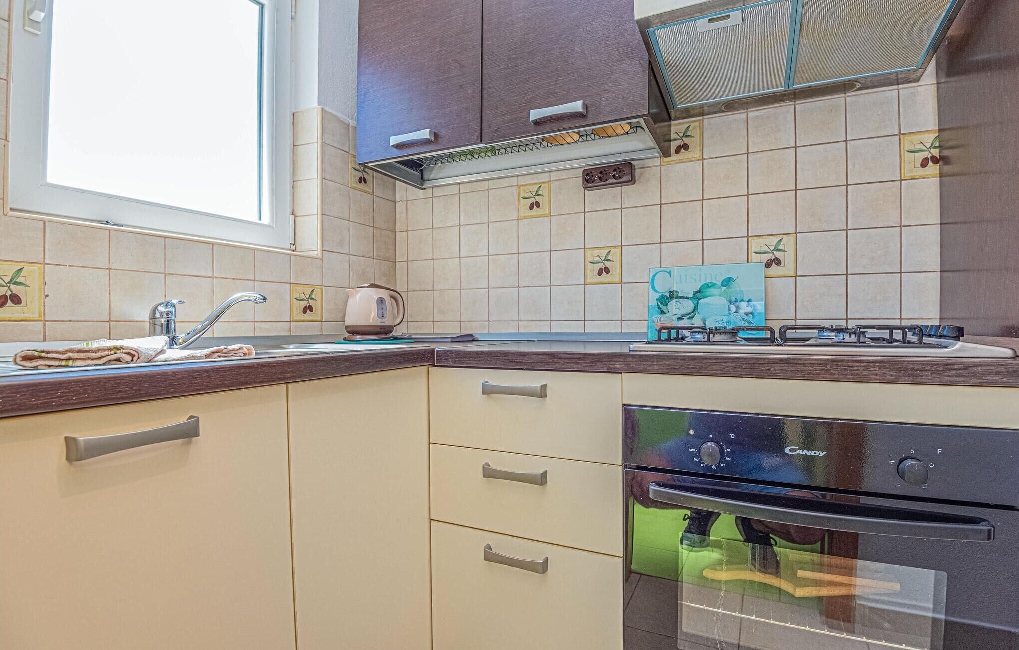 Een keuken met een spoelbak, kookplaat, oven en een raam.