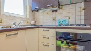 Eine Küche mit Spüle, Herd, Backofen und Fenster.
