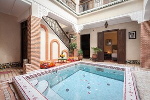 A pool area with a tiled floor, a staircase, and a seating area with cushions. - Riad Salman (Marrakech)