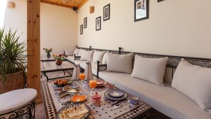 Un comedor con una mesa lista para el desayuno, un sofá y una planta en maceta.