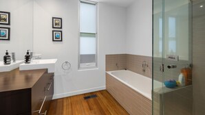 A modern bathroom with a glass shower enclosure, a bathtub, and a vanity with a sink. - Seasoon Luxury Amongst The Treetops Ocean Views (Lorne)
