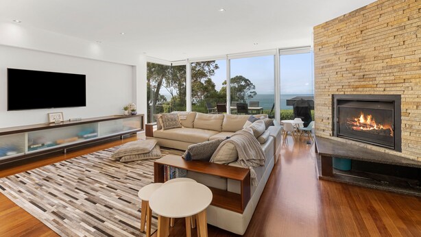 A modern living room with a large flat-screen TV, a sofa, a coffee table, and a fireplace. - Seasoon Luxury Amongst The Treetops Ocean Views (Lorne)