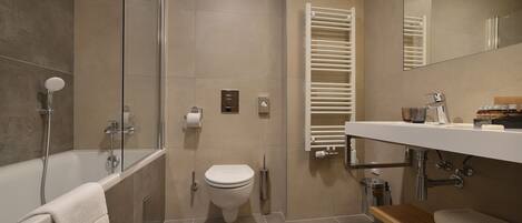 A modern bathroom with a bathtub, toilet, and shower.