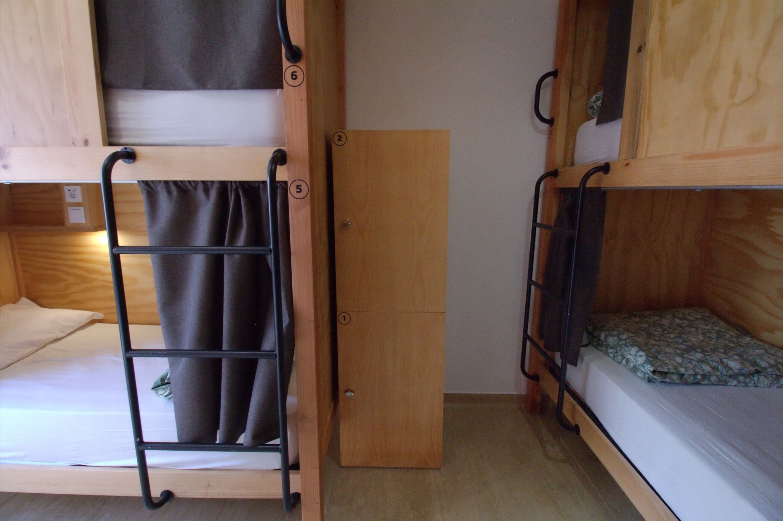 Habitación con literas, una puerta de madera y una escalera metálica.
