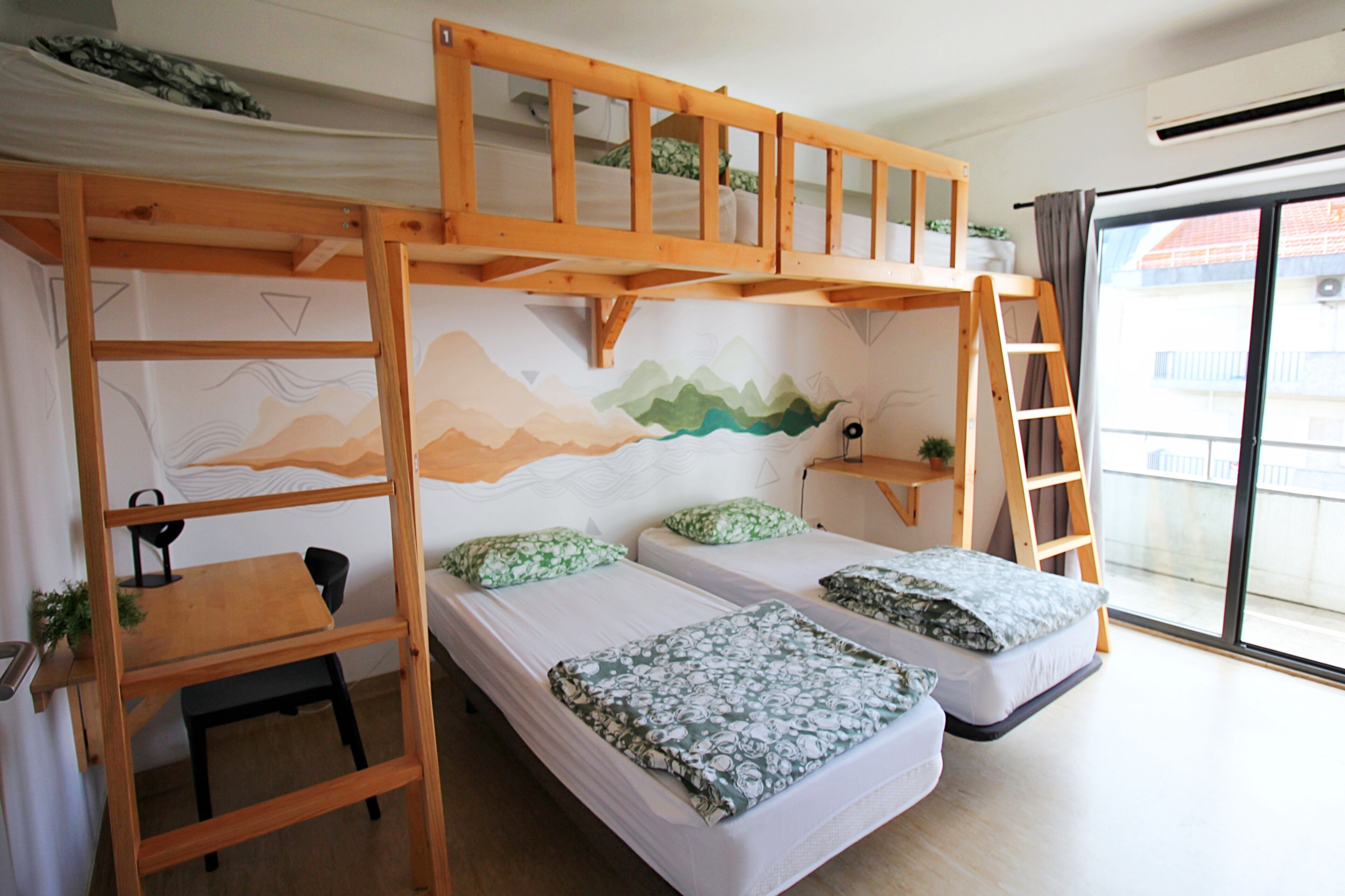 Una habitación tipo dormitorio con literas, un escritorio y vistas al exterior.
