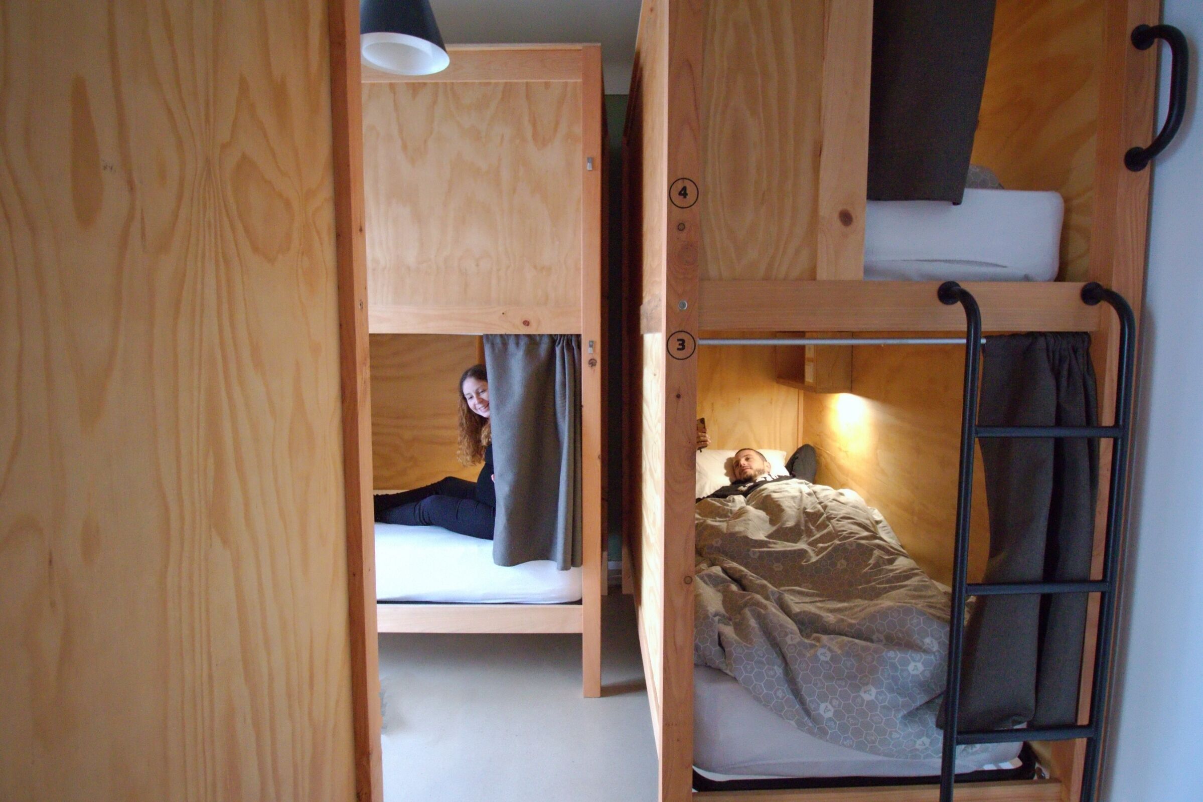 Habitación con literas, suelo de madera y una lámpara en el techo.