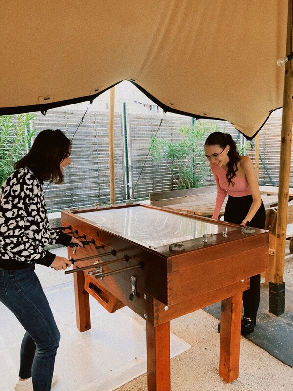 Two people playing foosball under a tent.