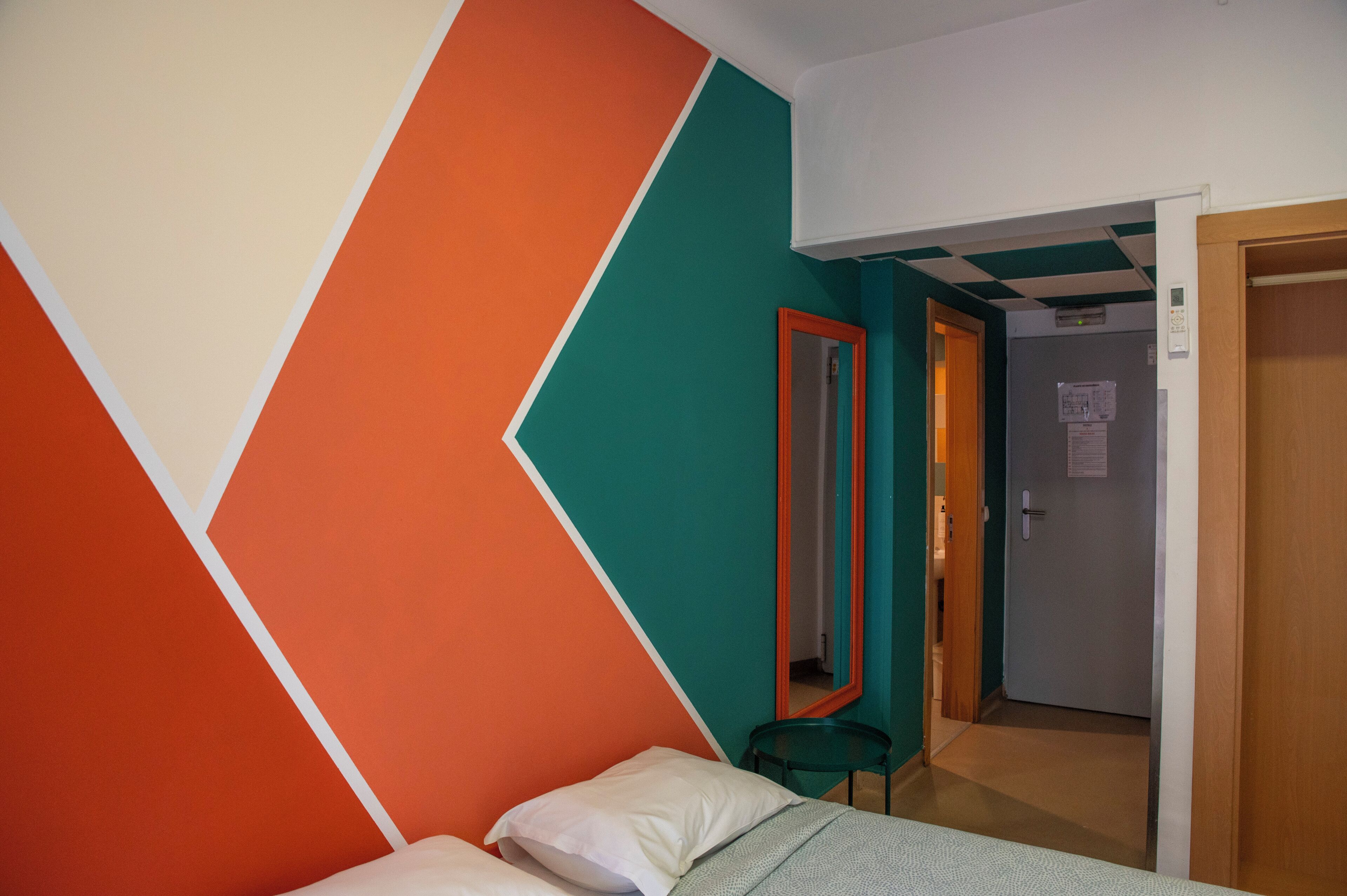 A room with a bed, a mirror, and a door leading to another room.
