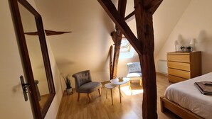 Une chambre à coucher comprenant un lit, une commode, une chaise, une petite table et un miroir.