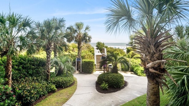 A landscaped pathway leading to a building with a sign, surrounded by palm trees and shrubs. - One-of-a-Kind 4 Bed / 4 Bath Oceanfront Retreat | ML03 (Myrtle Beach)