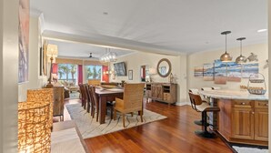 A spacious dining area with a wooden table and chairs, a kitchen with wooden cabinets, and a view of the outdoors. - One-of-a-Kind 4 Bed / 4 Bath Oceanfront Retreat | ML03 (Myrtle Beach)