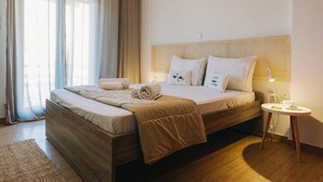 Una camera d'hotel moderna con un letto in legno, un comodino con una lampada e un'ampia finestra con tende.