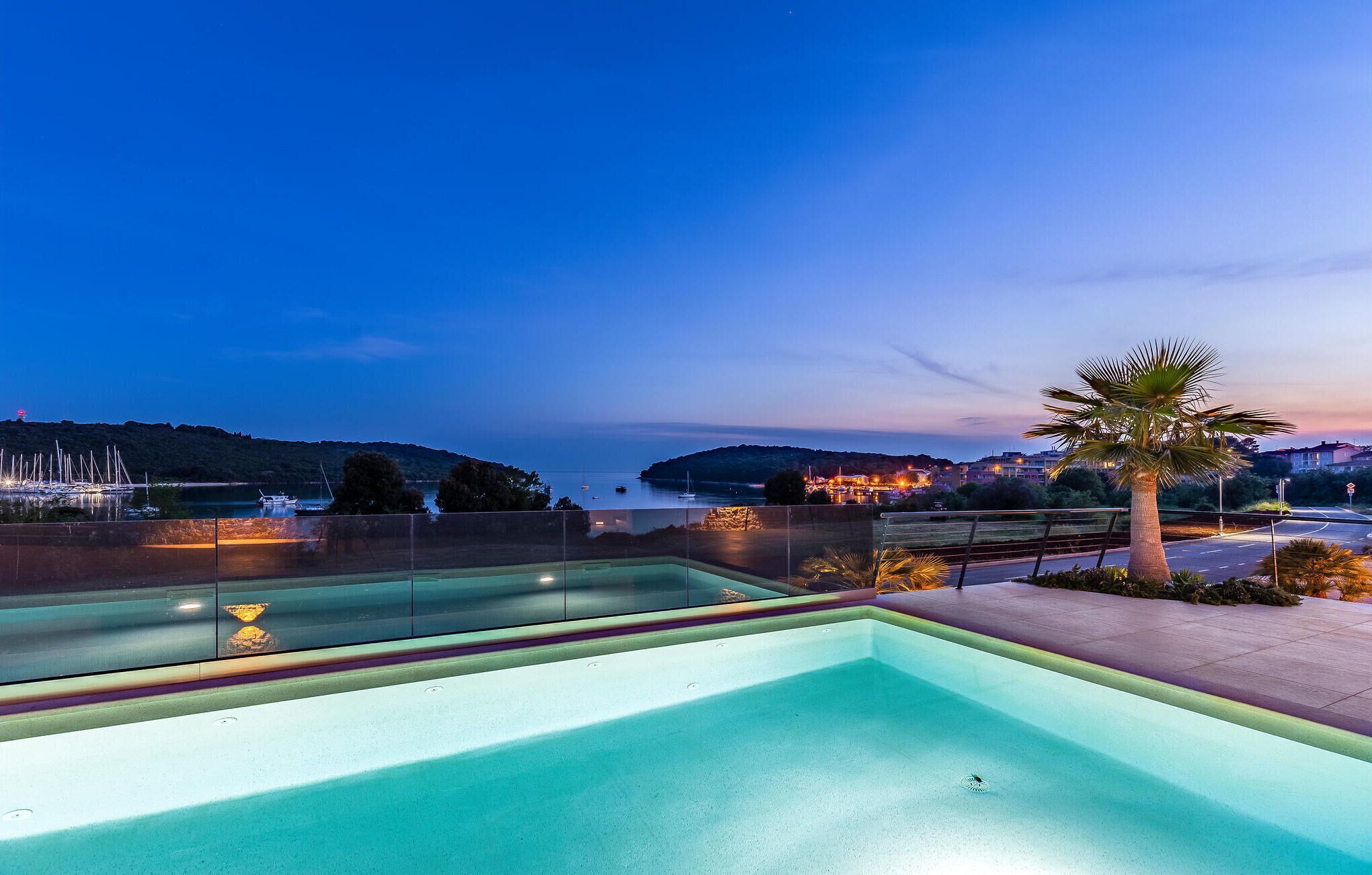 A swimming pool with a view of a coastal area at dusk.