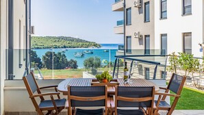 Ein Balkon mit Tisch und Stühlen mit Blick auf die Küste und Boote.