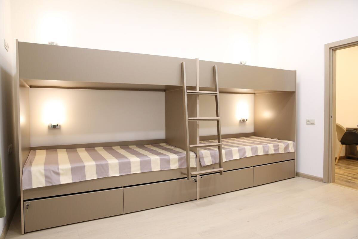 Ein Stockbett mit einer Leiter, zwei Nachttische und eine Wandleuchte.
