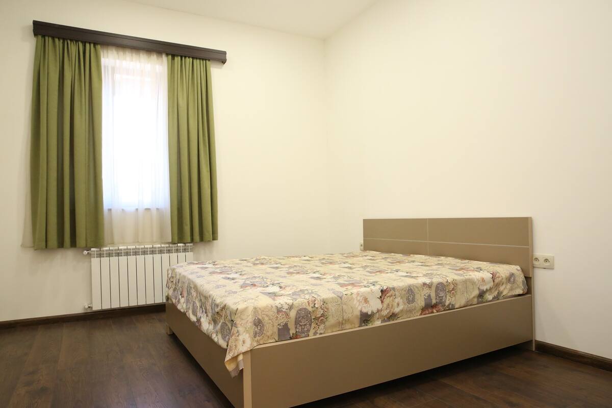 Ein Schlafzimmer mit einem Bett, einem Heizkörper und einem Fenster mit Vorhängen.