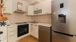 A modern kitchen with white cabinets, stainless steel appliances including a refrigerator, microwave, oven, and dishwasher. - Stunning Home in Zdrelac With Wifi and 4 Bedrooms (Pasman)