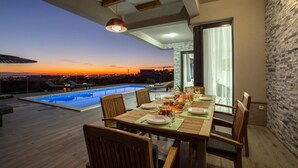 Zona pranzo con vista sulla piscina e sul tramonto.