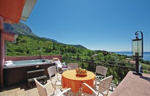 A terrace with a hot tub, outdoor seating, and a view of a lake and mountains.