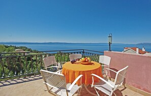 A balcony with a table set for two, overlooking a scenic view of the sea.