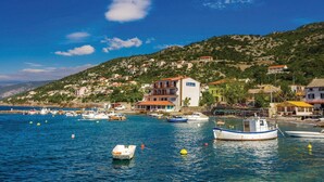 A coastal village with boats docked in the water, houses on a hillside, and a clear blue sky. - Amazing Home in Sveti Juraj With Wifi and 0 Bedrooms (Senj)