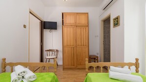 A room with two wooden beds, a wooden wardrobe, a television mounted on the wall, and a small table. - Beautiful Apartment in Omisalj With 1 Bedrooms and Wifi (Omisalj)