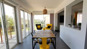 Un comedor moderno con una mesa grande y sillas amarillas, ventanas amplias y vistas a zonas verdes.