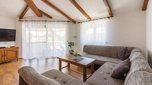 A living room with a wooden ceiling, a sofa, a coffee table, and a TV. - Beautiful Home in Pula With Wifi and 7 Bedrooms (Pula)
