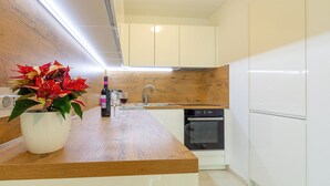Una cocina moderna con armarios blancos, encimera de madera, un lavabo, lavavajillas y una planta en maceta.