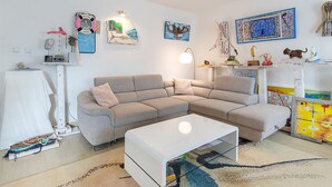 Una sala de estar moderna con un sofá seccional gris, una mesa de centro blanca y una alfombra estampada.