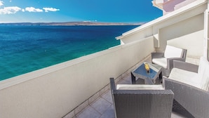 Ein Balkon mit Korbmöbeln mit Blick auf das klare, blaue Meer.