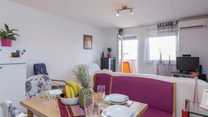 En matplats med ett bord dukat för två personer, en fruktskål och en tv-apparat i bakgrunden.