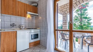Cozinha com armários de madeira, fogão a gás, forno e janela com vista para um jardim.