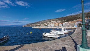 A coastal town with boats docked along the waterfront, a paved promenade, and buildings with red-tiled roofs. - Amazing Apartment in Senj With 3 Bedrooms and Wifi (Senj)