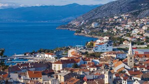 A coastal town with a mix of traditional and modern architecture, a prominent church, and a view of the sea and mountains in the background. - Amazing Apartment in Senj With 3 Bedrooms and Wifi (Senj)