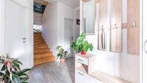 Ein Flur mit einer Holztreppe, einem Blumentopf und einem Holzschrank mit Spiegel.