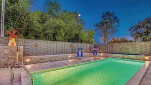 Ein Pool im Freien mit einer Steinmauer und zwei Liegestühlen.