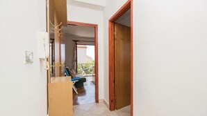 En gang der fører til en balkon med en stol og et bord, en trædør og en telefon på væggen.